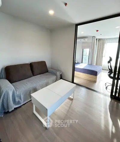 Modern apartment with cozy living room and bedroom, featuring sleek furniture and natural light.