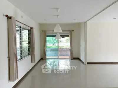 Spacious living room with large windows and sliding glass doors to balcony