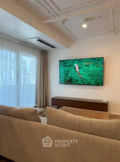 Modern living room with large TV and comfortable sofa, perfect for relaxation and entertainment.