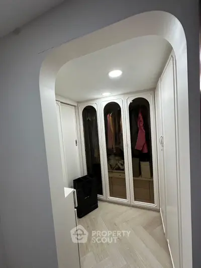 Spacious walk-in closet with elegant white cabinetry and ample storage space.
