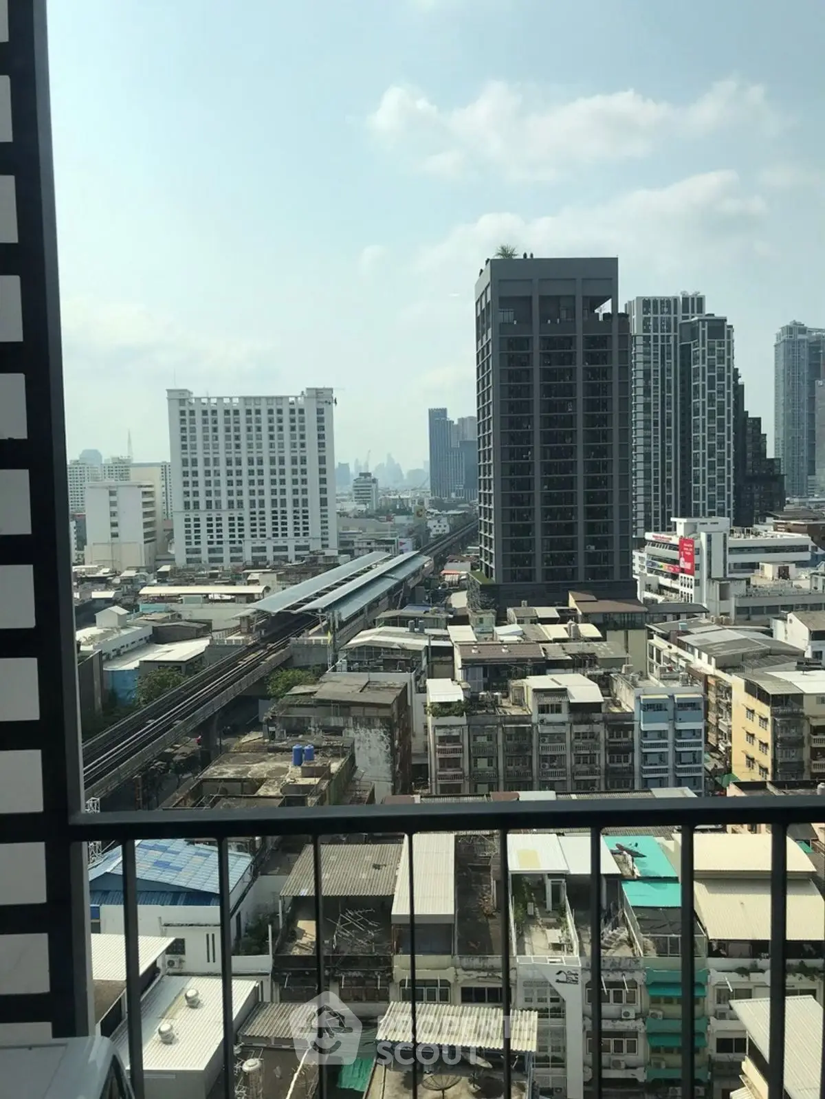 Stunning cityscape view from a high-rise balcony overlooking urban skyline and railway.