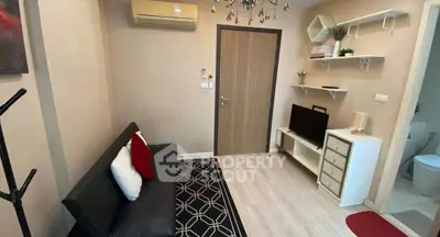 Cozy living room with modern decor and air conditioning, featuring a sleek black sofa and stylish shelving.