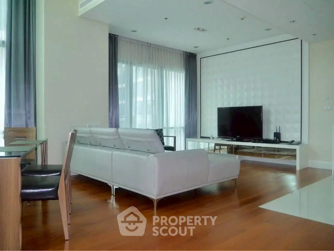 Modern living room with sleek furniture and large TV, featuring hardwood floors and stylish decor.