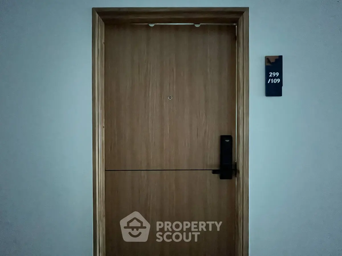 Modern apartment door with electronic lock and room number plaque, showcasing secure entry.