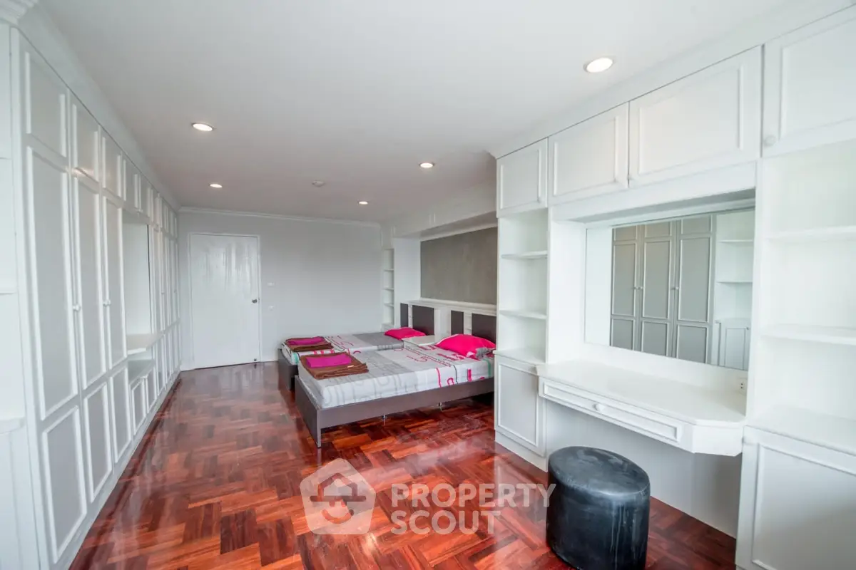 Spacious bedroom with elegant wood flooring and built-in storage