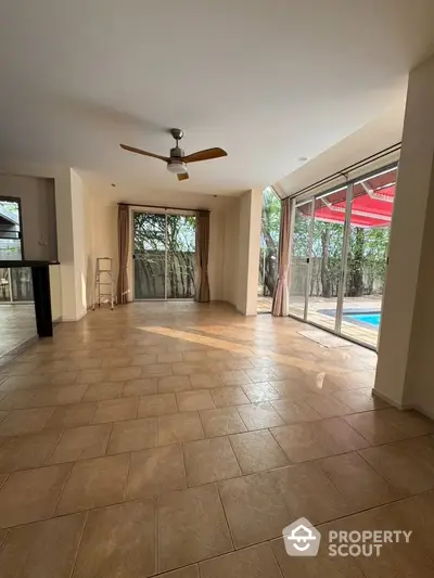 Spacious living room with pool view and ceiling fan, perfect for relaxation.