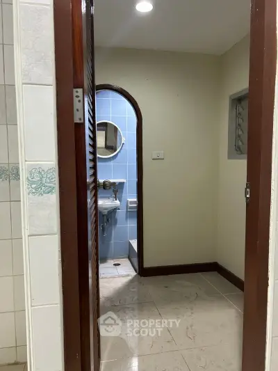 Cozy bathroom with blue tiles and round mirror, perfect for a compact living space.