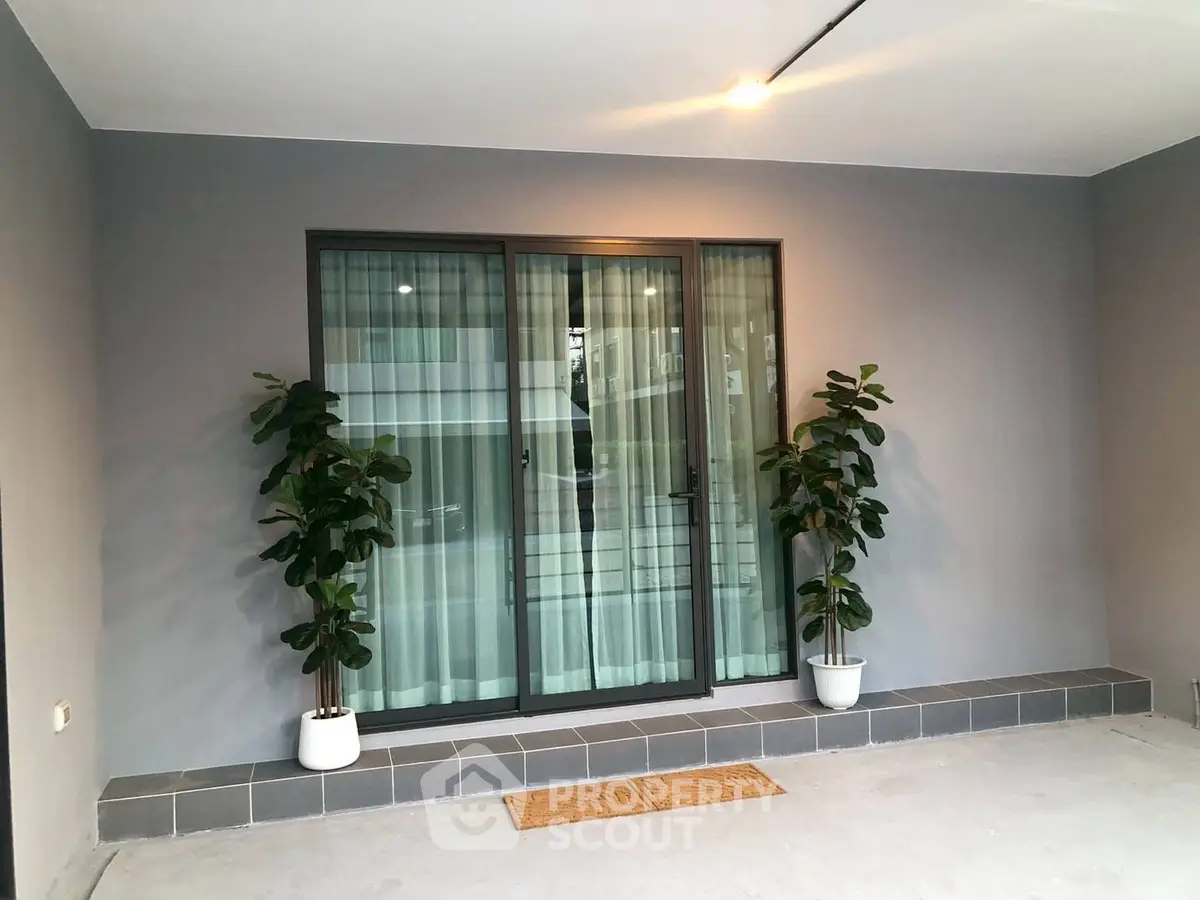 Modern home entrance with sliding glass doors and potted plants