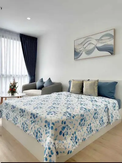 Modern bedroom with stylish decor and natural light, featuring a cozy bed and elegant sofa.