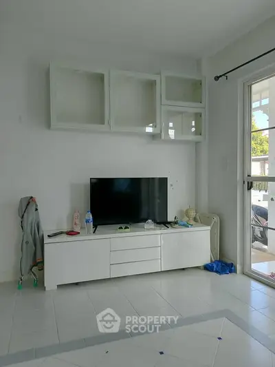 Modern living room with sleek TV unit and glass cabinets, bright natural light.