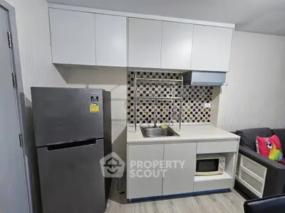 Modern compact kitchen with sleek cabinetry and stainless steel fridge in a cozy apartment.