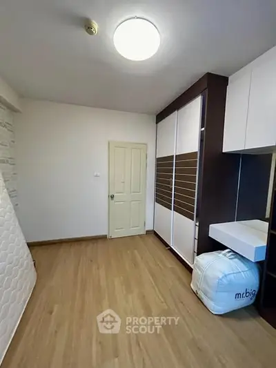 Spacious bedroom with wooden flooring and ample storage space.