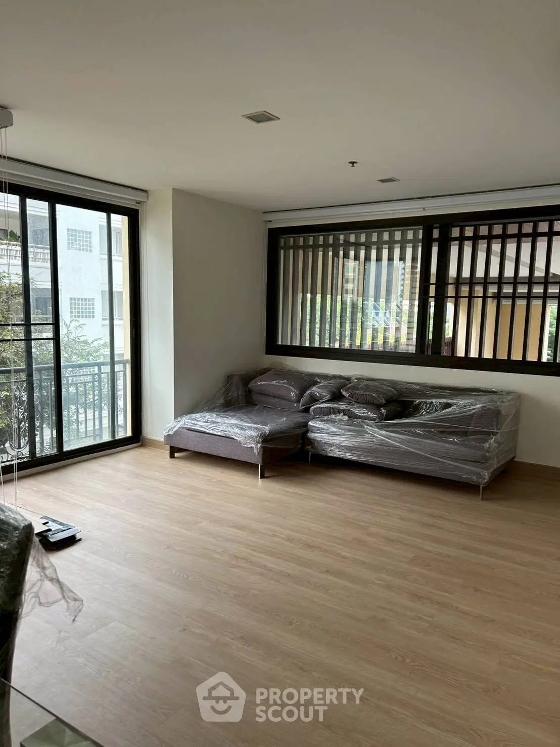 Spacious living room with large windows and modern furniture in a bright apartment.