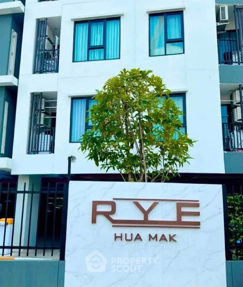 Modern apartment building exterior with RYE Hua Mak signage and lush greenery.