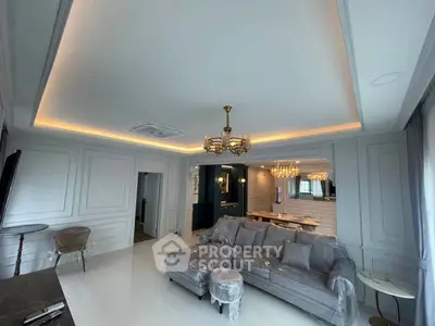 Luxurious living room with elegant chandelier and plush gray sofa in modern apartment.