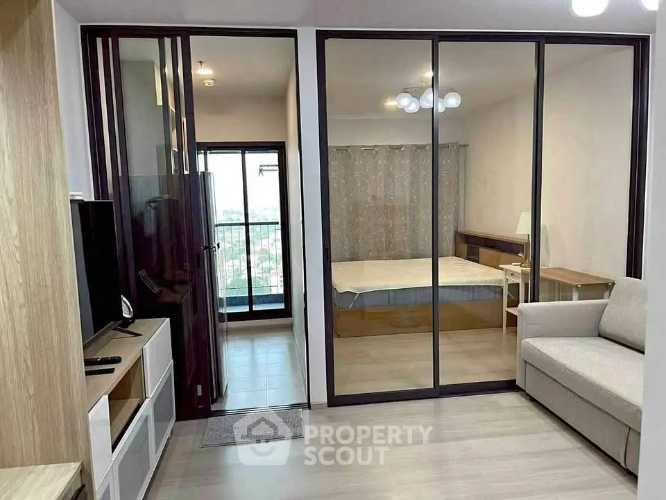 Modern apartment with glass partition, cozy living area, and bedroom with balcony view.