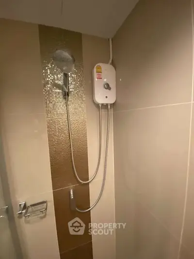 Modern bathroom with sleek showerhead and water heater, featuring elegant tile design.