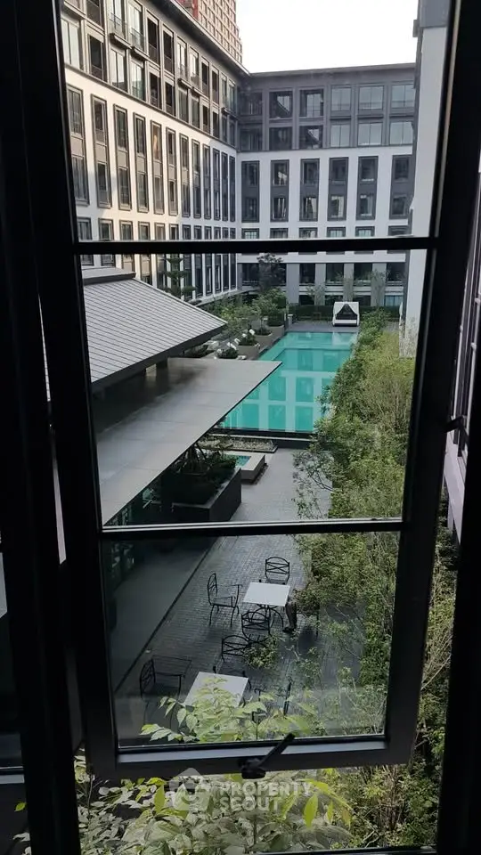 Luxurious apartment complex with stunning pool view from window, showcasing modern architecture and lush greenery.