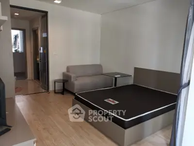 Modern studio apartment with sleek furniture, wood flooring, and ample natural light, perfect for singles or couples.