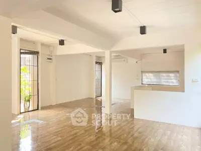 Spacious open-plan living area with polished wooden floors and modern lighting.