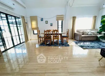 Spacious living room with elegant dining area and cozy sofa, featuring large windows and stylish decor.