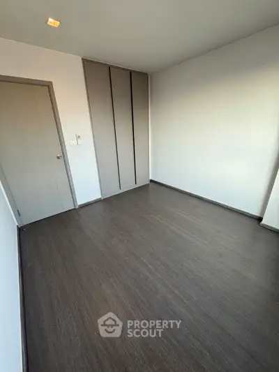 Spacious empty room with sleek wooden flooring and built-in closet, perfect for customization.