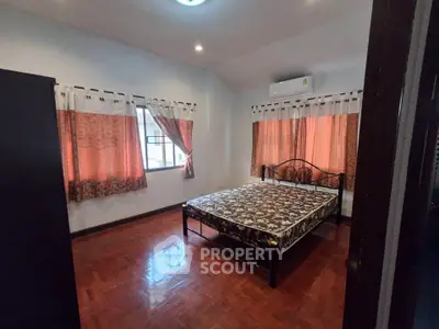 Spacious bedroom with elegant curtains and wooden flooring, featuring a comfortable bed and air conditioning.