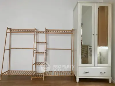 Spacious bedroom with elegant wardrobe and wooden shelving unit, perfect for organized living.