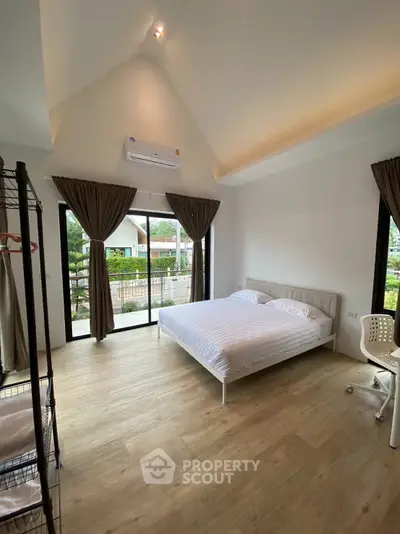 Spacious bedroom with large windows and modern decor in a bright, airy home.
