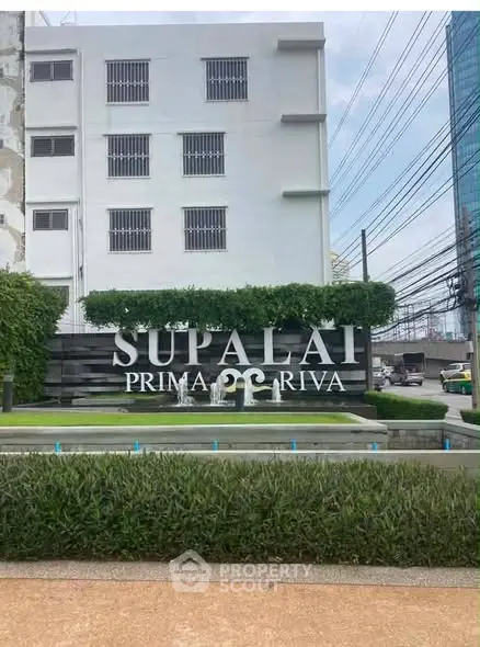 Modern building exterior with Supalai Prima Riva signage and lush greenery.