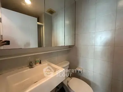 Compact bathroom with modern fixtures and tiled walls, featuring a sleek sink and toilet.
