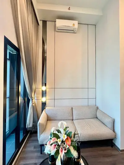 Modern living room with stylish sofa and air conditioning, featuring elegant decor and floor-to-ceiling windows.