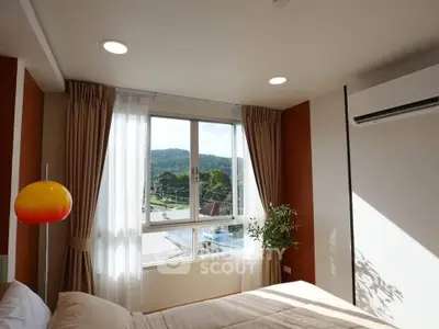 Bright bedroom with large window and scenic view, featuring modern decor and air conditioning.