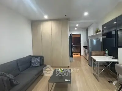 Modern living room with sleek kitchen, featuring a cozy sofa and stylish decor in a contemporary apartment.