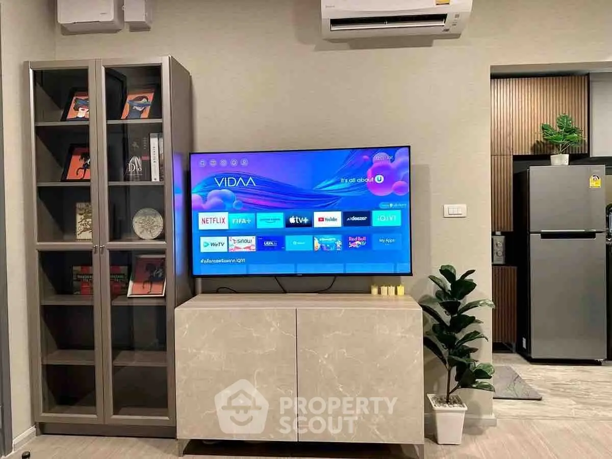 Modern living room with smart TV, stylish cabinet, and sleek refrigerator in open layout.