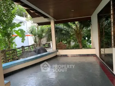 Spacious covered patio with lush garden view, perfect for outdoor relaxation and entertainment.
