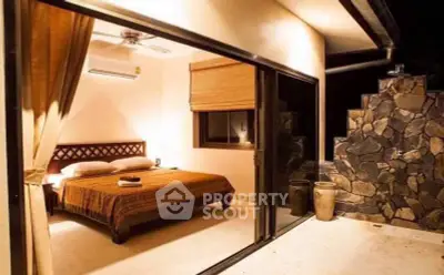 Luxurious bedroom with stone wall and sliding glass doors opening to a serene outdoor space.