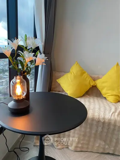 Cozy living room corner with stylish lamp, yellow cushions, and city view.