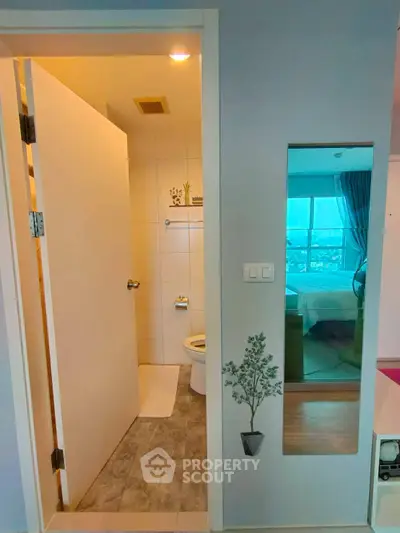 Modern apartment with bathroom and bedroom view, featuring sleek design and natural lighting.