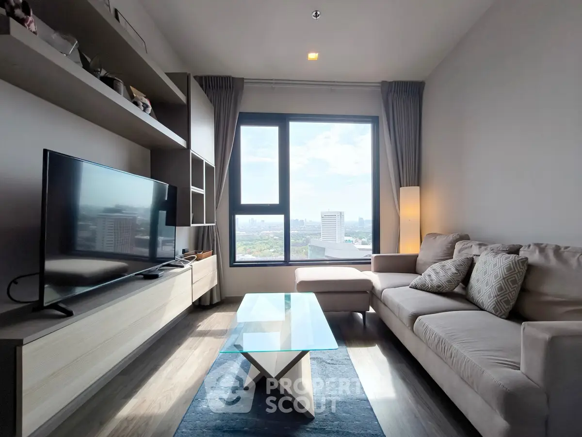 Modern living room with large window and city view, featuring stylish furniture and a sleek TV setup.