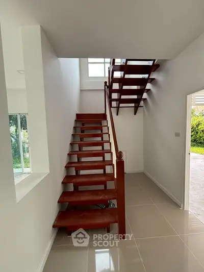 Modern staircase with wooden steps in a bright, minimalist home interior.