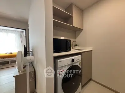 Modern compact laundry area with washer and microwave in sleek apartment