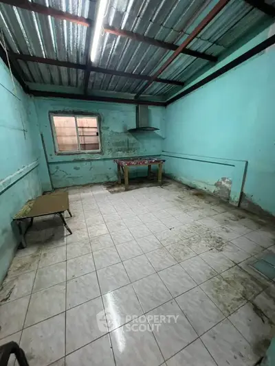Spacious room with potential for renovation, featuring tiled floor and metal roof, ideal for creative transformation.