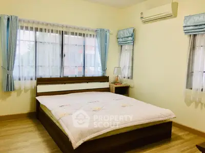 Cozy bedroom with large windows and air conditioning, perfect for relaxation.