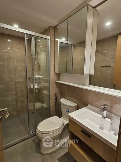 Modern bathroom with glass shower, sleek vanity, and elegant tile design.