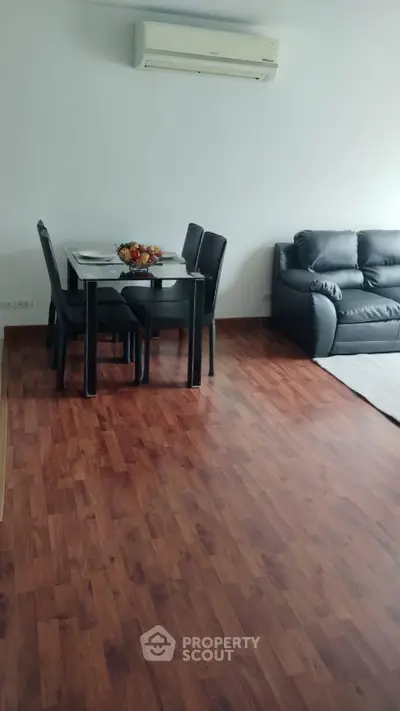 Spacious living room with wooden flooring, modern furniture, and air conditioning unit.