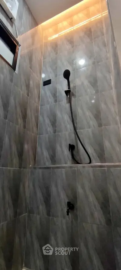 Modern bathroom shower with sleek gray tiles and ambient lighting