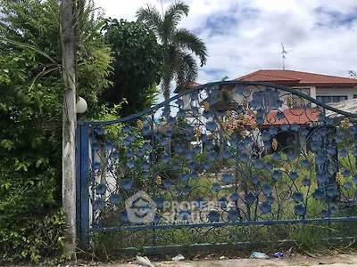 Charming suburban house with ornate blue gate and lush greenery