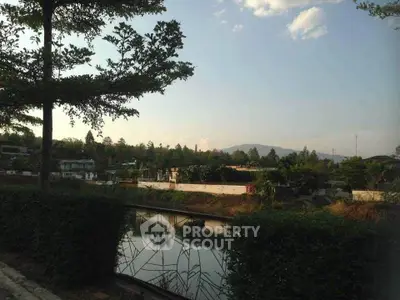 Scenic view of serene residential area with lush greenery and tranquil water feature.