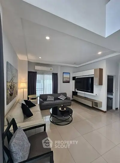 Spacious modern living room with sleek furniture and large TV, perfect for relaxation and entertainment.